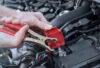 Hands of car mechanic using car battery jumper cable. panoramic
